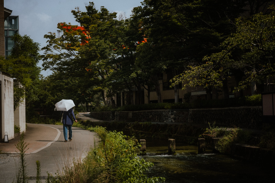Il grande torii vermiglio di Heian Jingū con un uomo e una figura con l'ombrello alle strisce, Kyoto